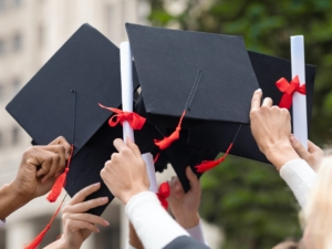 Graduation hats and diplomas in students hands, closeup
