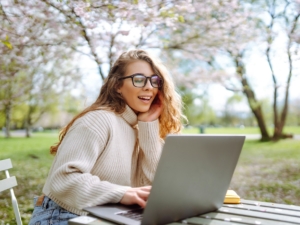Happy female freelancer sitting in the office with a laptop. Nature and urban lifestyle concept.